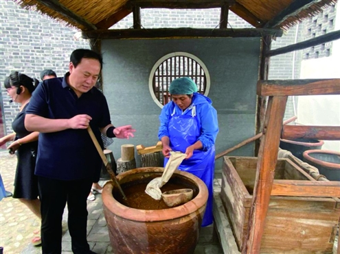 莱芜口镇南肠传统制作技艺传承人刘峰(左前)介绍制作口镇南肠必备调料酱油的过程